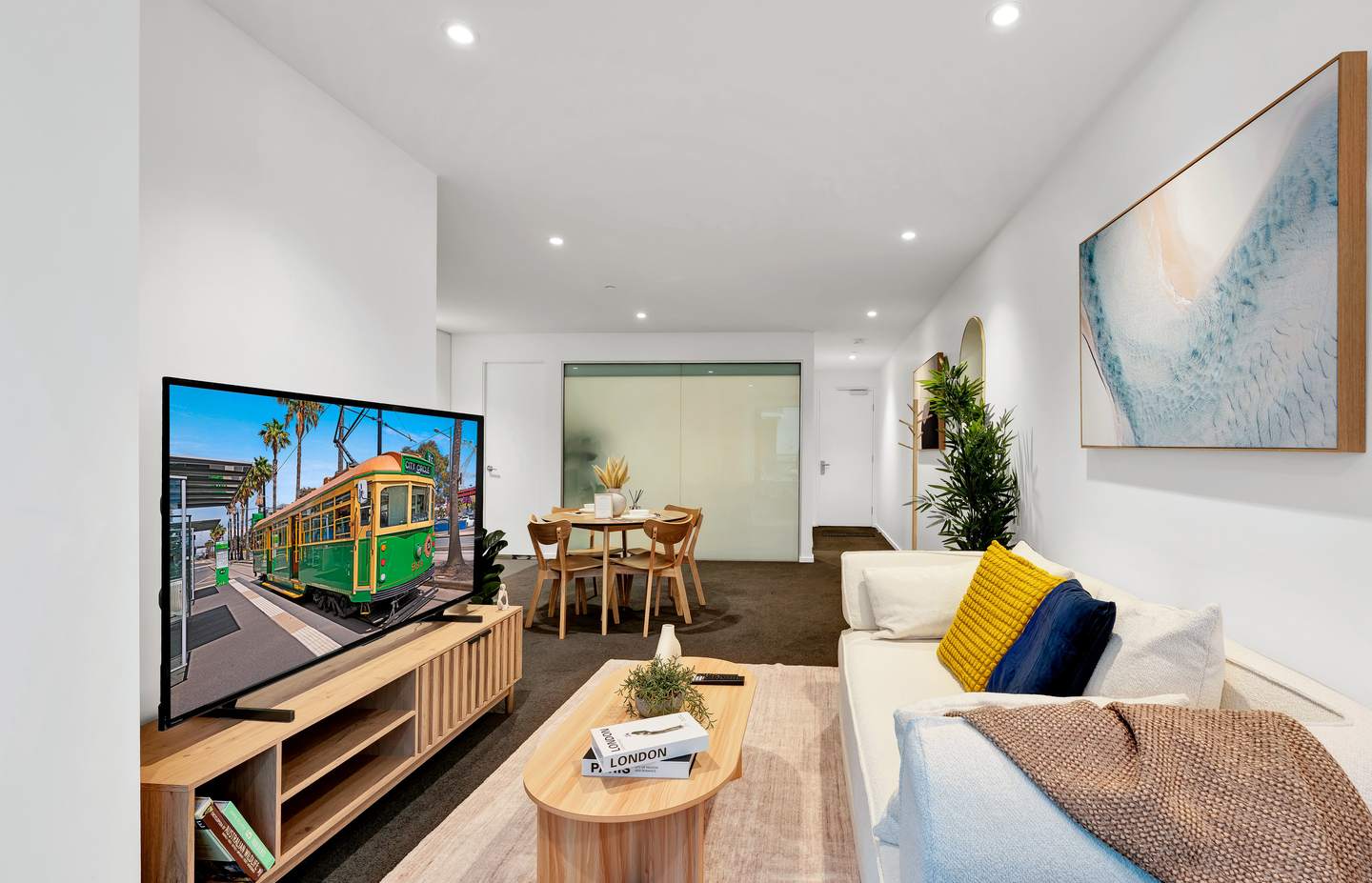 Aurora: living and dining — the sofa and the 65-inch smart television on one side, the dining table for four on the other