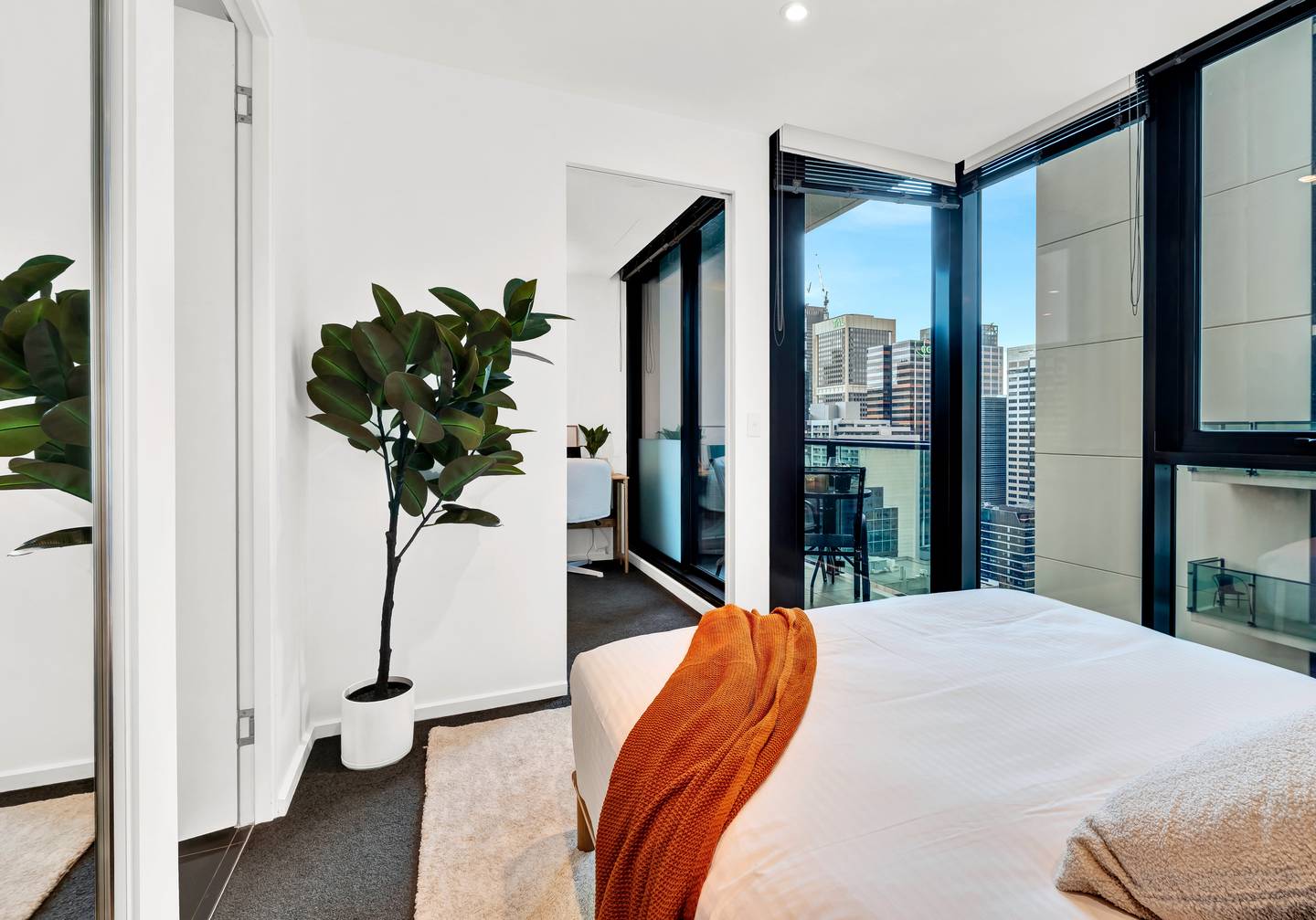 Aurora: master bedroom — corner windows the full height of the wall, with the city view from Level 27