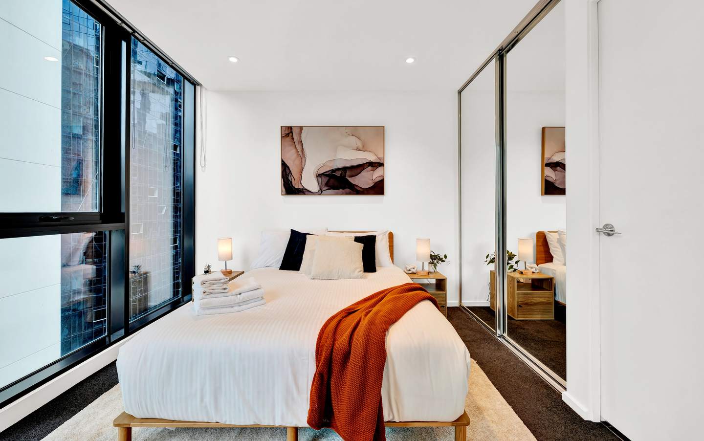 Aurora: master bedroom — queen bed on a light oak frame, dressed in hotel-grade linen