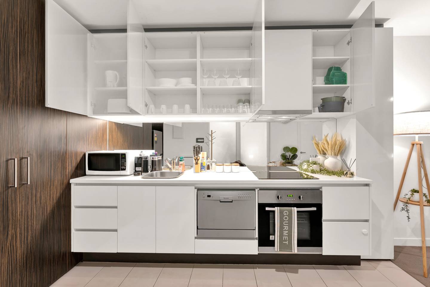 Madison: kitchen — cupboards stocked for cooking and hosting, with crockery, cutlery and wine glasses for six
