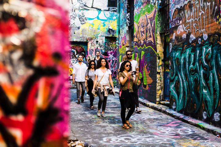 Visitors walk through Hosier Lane in Melbourne, its walls covered in street art.