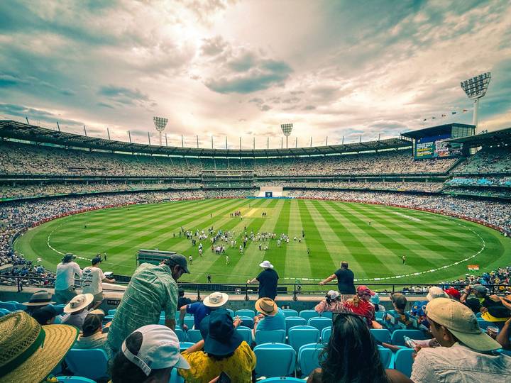 The Melbourne Cricket Ground during a cricket match, the stands packed under a bright sky.